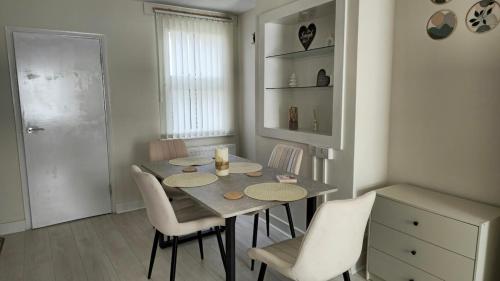 ein Esszimmer mit einem Tisch und weißen Stühlen in der Unterkunft 2 Bed Cottage Retreat in central location in Slough