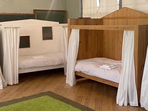 two bunk beds in a room with a green rug at 'Yamaneko Hotel 'Saunas, Serenity & Feline Friends in Miyoshi