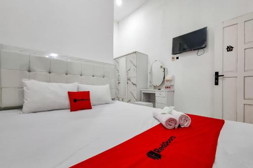 a bedroom with a white bed with a red blanket at RedDoorz at Barra Homestay near RSUD Batang in Batang
