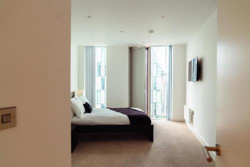 een slaapkamer met een bed en 2 grote ramen bij Luxury 2 Bed apartment Deansgate in Manchester