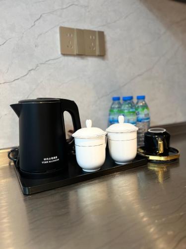 a black tea kettle and three white bowls on a tray at Times Mansion king size standard room in Freetown