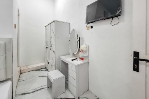a bathroom with a sink and a mirror and a tv at RedDoorz at Barra Homestay near RSUD Batang in Batang