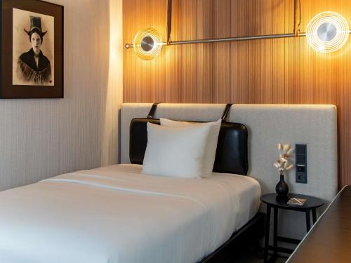 a bedroom with a white bed with a picture on the wall at MUZE Hotel Dusseldorf - Handwritten Collection in Düsseldorf
