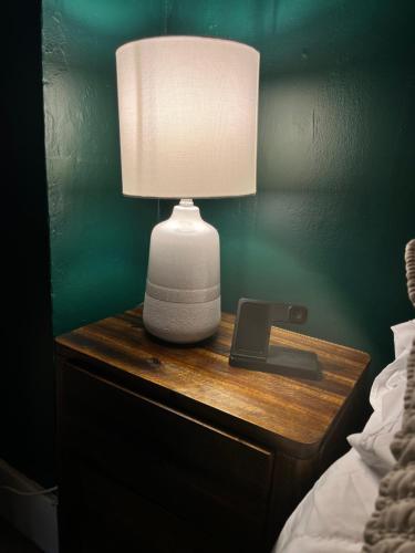 a table with a lamp on a nightstand next to a bed at Cozy 1bd apartment in the heart of Liverpool NY in Liverpool