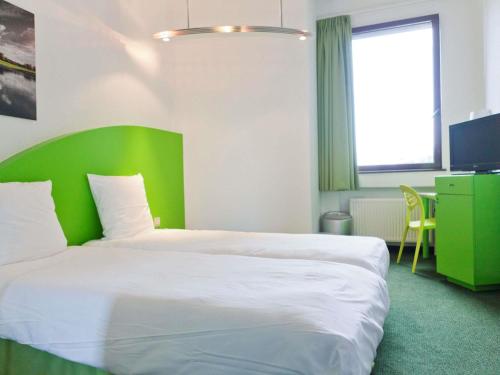 a bedroom with a large bed with a green headboard at Hotel Siru Brussels in Brussels