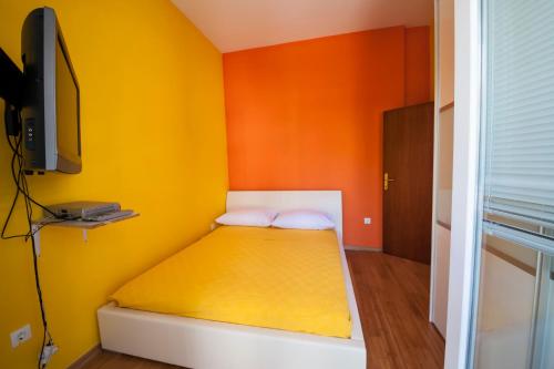 a small bedroom with a yellow and orange wall at Apartment May in Mali Lošinj