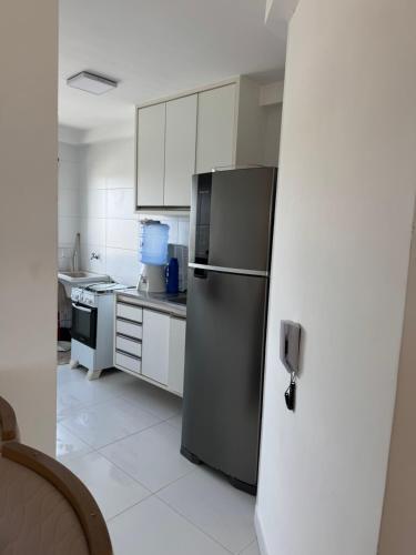 a kitchen with a stainless steel refrigerator and white cabinets at Seu apartamento em Ilhéus in Ilhéus