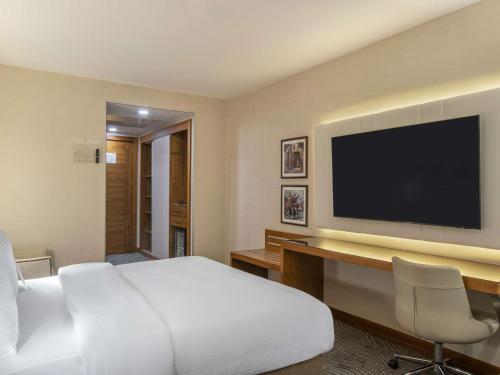 a hotel room with a bed and a flat screen tv at Mercure Ankara Kızılay in Ankara