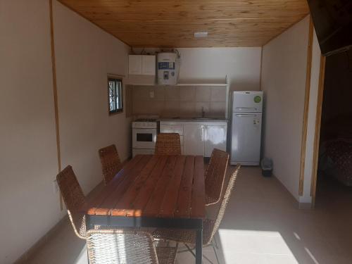 een keuken met een houten tafel en stoelen en een koelkast bij Cabañas Pie del Plata in Mendoza