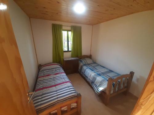 een kleine kamer met twee bedden en een raam bij Cabañas Pie del Plata in Mendoza