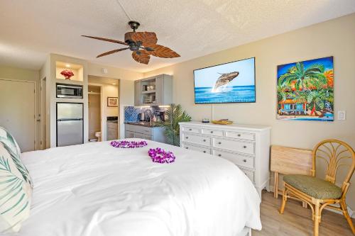 a bedroom with a large white bed and a kitchen at Maui Banyan Studio, King Bed, Steps to Kam2 Beach in Wailea