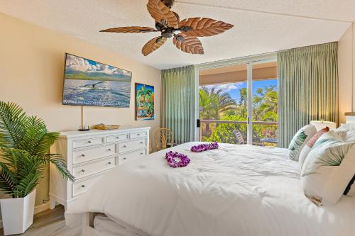 a bedroom with a large white bed with purple flowers on it at Maui Banyan Studio, King Bed, Steps to Kam2 Beach in Wailea