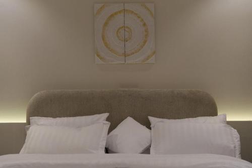 a bed with white pillows and a picture on the wall at نسيم الحرم in Ash Shishah