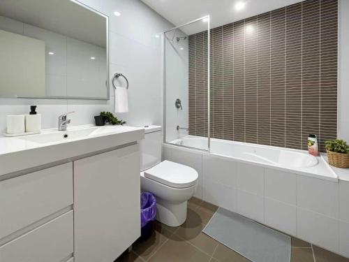 a white bathroom with a toilet and a tub and a sink at The River at Parramatta wif Free parking in Sydney