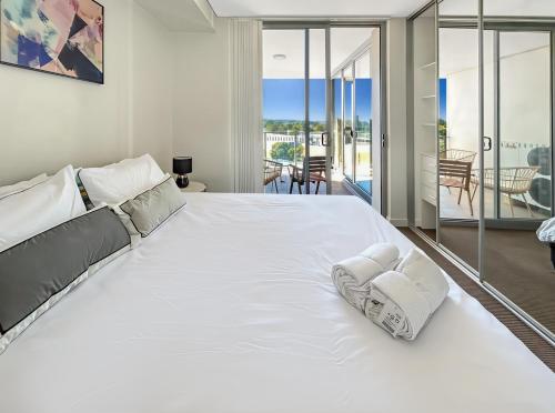 a large white bed in a bedroom with a balcony at The River at Parramatta wif Free parking in Sydney