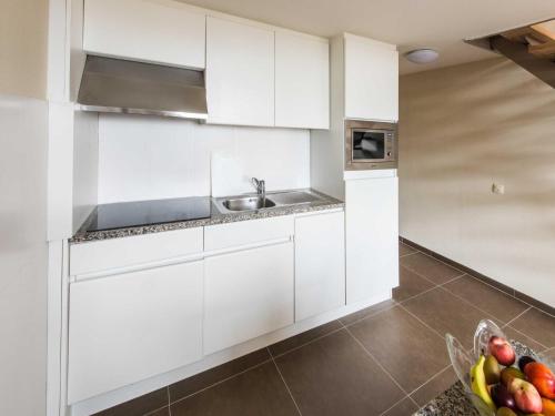 a white kitchen with a sink and a bowl of fruit at Deluxe superior apartment in Antwerp in Antwerp