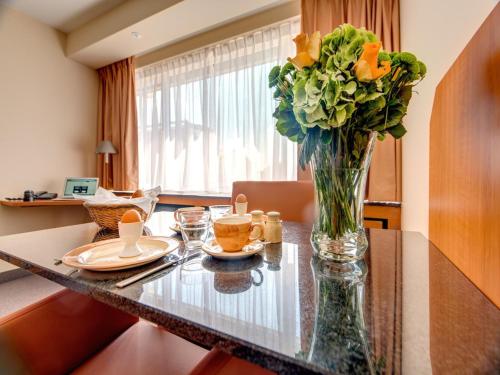 Un jarrón lleno de flores sobre una mesa. en Standard room in Antwerp near Grand Palace, en Amberes