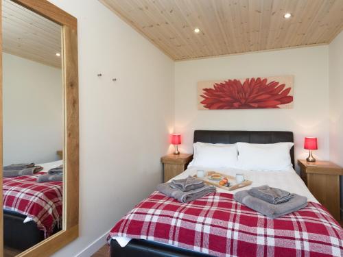 a bedroom with a bed with a red and white blanket at Broad Reach - 28121 in Fritton Norfolk
