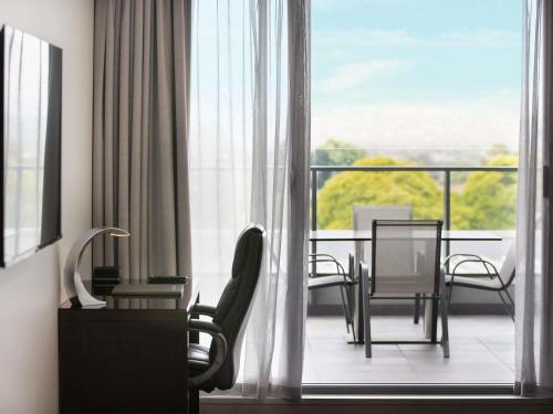 a room with a balcony with a table and chairs at The Sebel Melbourne Kew in Melbourne
