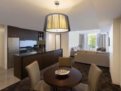a living room and kitchen with a table and chairs at The Sebel Melbourne Kew in Melbourne