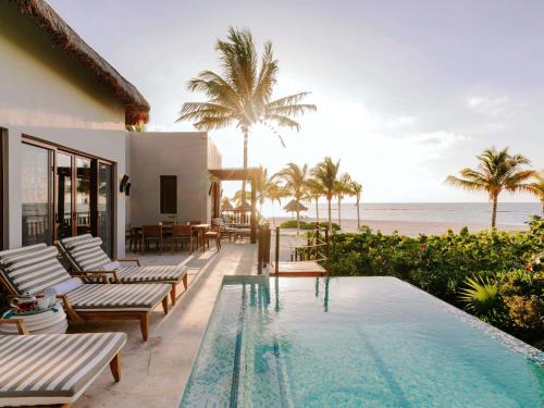 a villa with a swimming pool next to the beach at Fairmont Mayakoba in Playa del Carmen
