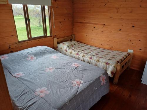 a bedroom with two beds in a log cabin at Casa 1 Los Piamonteses 3 personas in Juan L. Lacaze