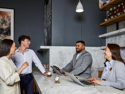 a group of people sitting around a table with laptops at Aparthotel Adagio London Brentford in Brentford