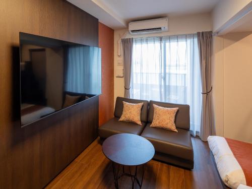 a living room with a couch and a tv and a table at The Riverfront Residence Nishihiroshima in Hiroshima