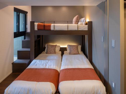 two bunk beds in a room with a staircase at The Riverfront Residence Nishihiroshima in Hiroshima