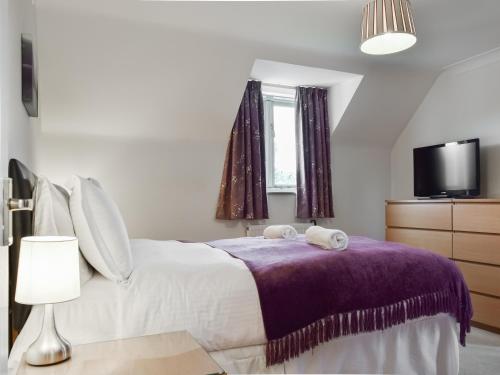 a bedroom with a bed with a purple blanket at Renwood in Eynsham