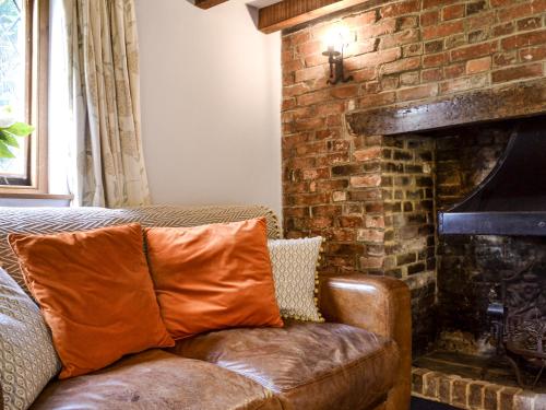 a couch sitting in front of a brick fireplace at The Old Thatched Cottage in Tenterden