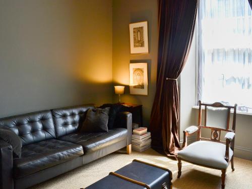 a living room with a leather couch and a chair at Blackbird House in Alnwick