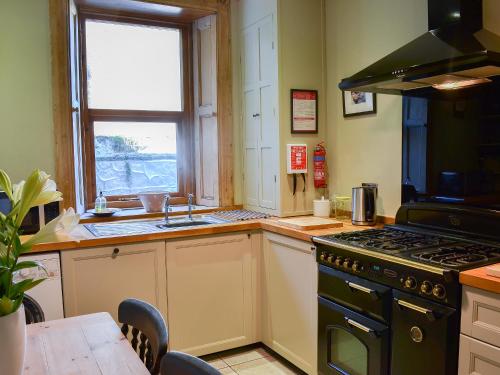 a kitchen with a stove and a sink and a table at Blackbird House in Alnwick