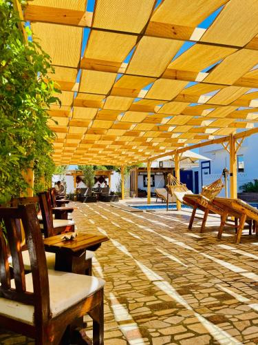 a patio with wooden tables and benches under a wooden roof at Dolphina hotel & Restaurant in Dahab