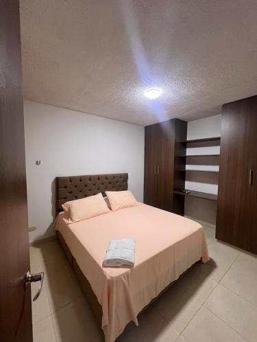 a bedroom with a bed with pink sheets and brown cabinets at Silvia Maria Lodging House in Valledupar