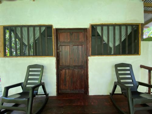two chairs sitting in front of a house with a door at GreenPoint Drake Bay in Drake