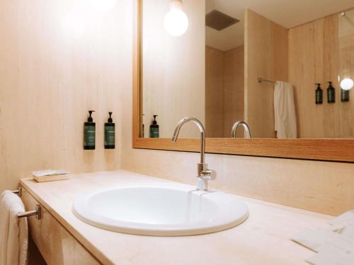 a bathroom with a white sink and a mirror at Mövenpick Hotel Bari in Bari