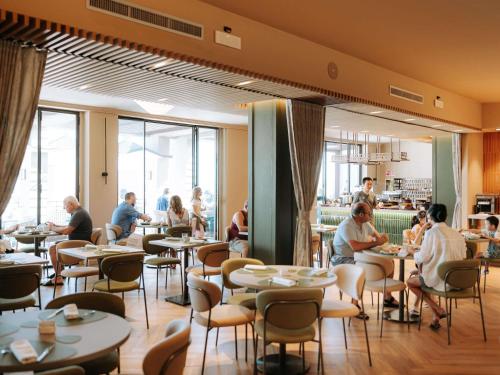 a restaurant with people sitting at tables at Mövenpick Hotel Bari in Bari