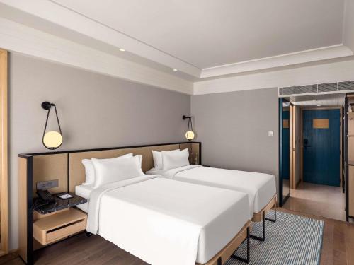 a hotel room with two beds and a mirror at Pullman Chennai Anna Salai - Premium Brand By Accor in Chennai
