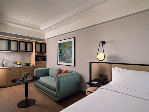 a hotel room with a bed and a chair and a kitchen at Pullman Chennai Anna Salai - Premium Brand By Accor in Chennai