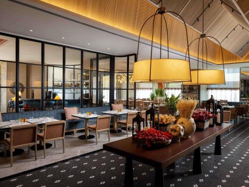 a dining room with tables and chairs and windows at Pullman Chennai Anna Salai - Premium Brand By Accor in Chennai