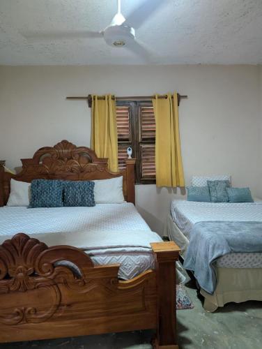 two beds in a bedroom with yellow curtains at El Conuco de Jose 