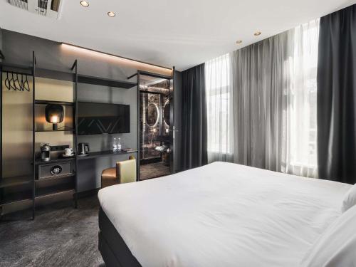 a bedroom with a large bed and a television at Le Marin Hotel Rotterdam City - Handwritten Collection in Rotterdam