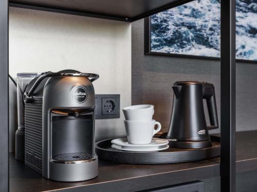 a coffee maker and a cup on a shelf at Le Marin Hotel Rotterdam City - Handwritten Collection in Rotterdam