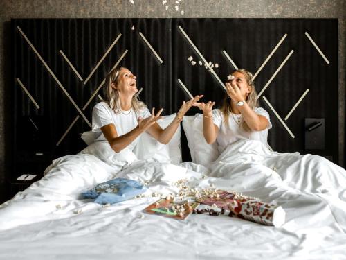 two women laying in bed and playing with matches at Le Marin Hotel Rotterdam City - Handwritten Collection in Rotterdam