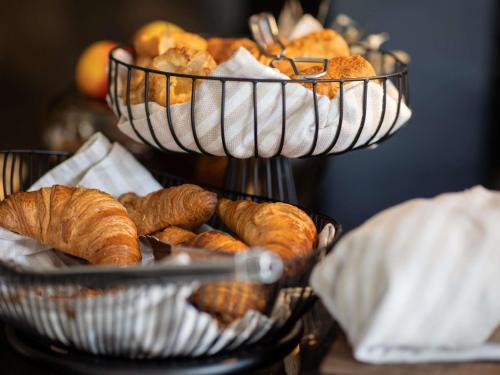 two baskets filled with croissants and breads on a table at Le Marin Hotel Rotterdam City - Handwritten Collection in Rotterdam