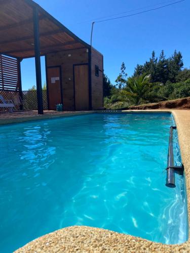 une piscine avec un bâtiment en arrière-plan dans l'établissement Cabaña Parcela Nativo, à Los Álamos