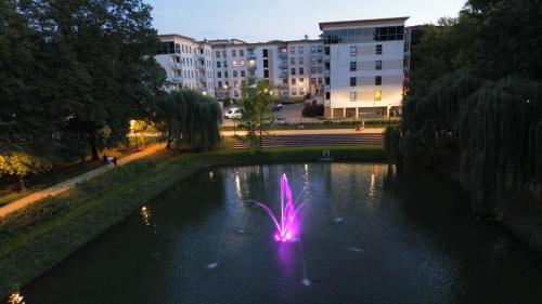 a fountain in the middle of a pond in a city at EUROPA22 Apartament RELAKS z JACUZZI w samym sercu miasta Prestiżowe osiedle z widokiem na park i staw z fontannami Szybkie i Łatwe Zameldowanie in Tomaszów Mazowiecki