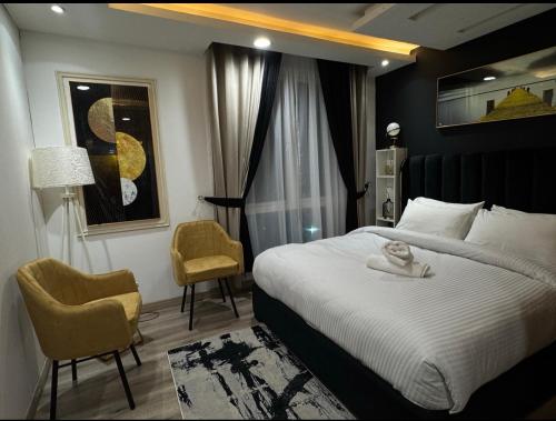 a bedroom with a large bed and two chairs at Gold Crest Executive Hotel Apartments City View DHA Lahore in Lahore