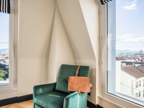 a green chair in a room with a window at MADISON Saint Jean de Luz - Handwritten Collection in Saint-Jean-de-Luz